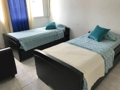 two beds in a room with blue pillows on them at Los delfines in Cartagena de Indias