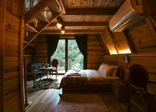 a bedroom in a log cabin with a bed and a table at bungalove tatil köyü in Çamlıhemşin