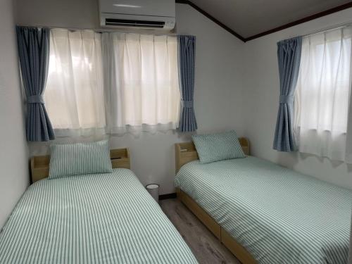 Enoshima HOME2 - Vacation STAY 20227v في فوجيساوا: سريرين في غرفة بها نوافذ وستائر