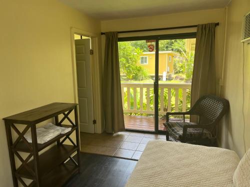 a bedroom with a bed and a view of a balcony at Aaron’s cottage in Hilo