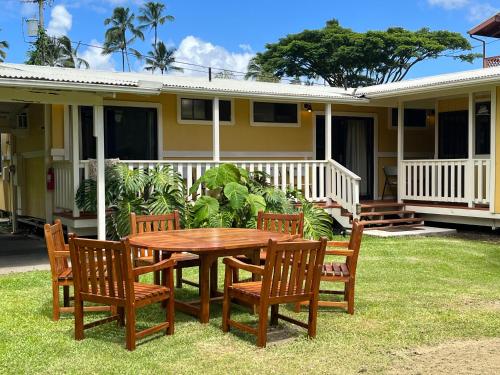 a wooden table and chairs in front of a house at Aaron’s cottage in Hilo