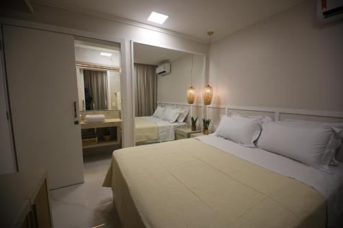 a bedroom with a large white bed and a mirror at Flat Beira Mar in Fortaleza