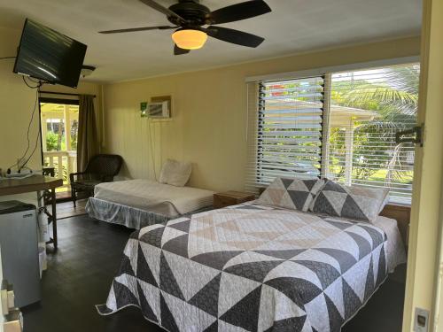 Aaron’s cottage في هيلو: غرفة نوم بسرير ومروحة سقف