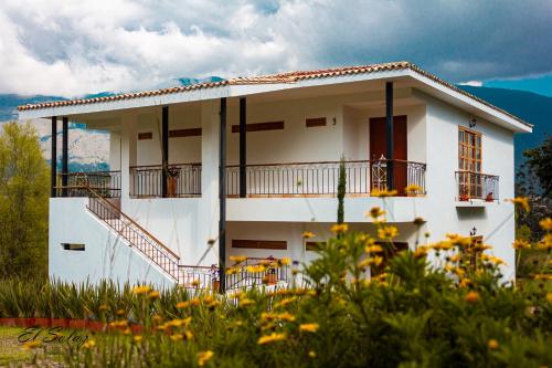 a white house with a staircase in front of it at Hospedaje campestre - El Solaz Suites in Villa de Leyva