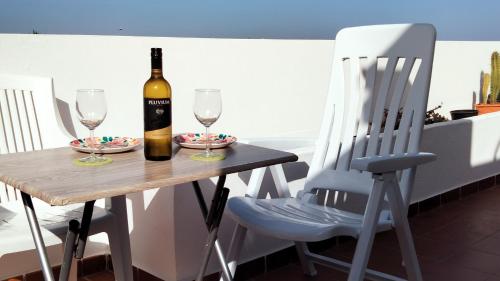 een fles wijn zittend op een tafel met twee glazen bij Mi habitación de invitados in Puerto del Rosario
