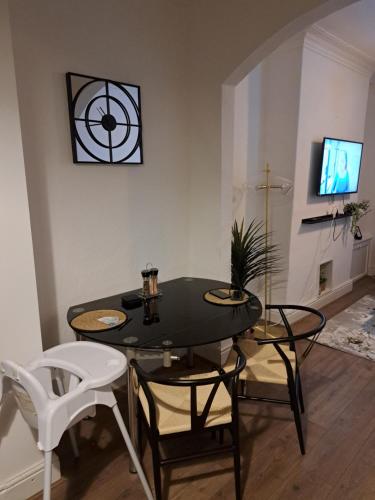 a dining room with a table and chairs and a tv at LouLuxe Modern Cosy Home in Manchester