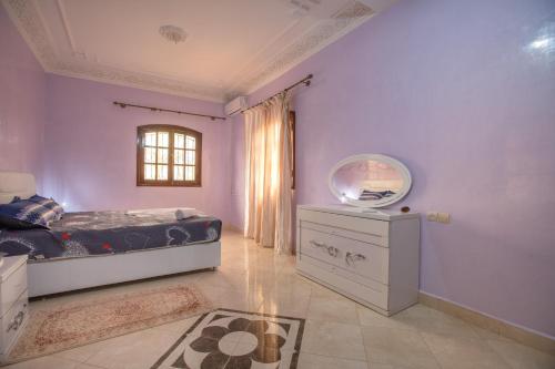 a bedroom with purple walls and a bed and a mirror at Villa en pleine campagne avec vue sur l'atlas in Marrakech