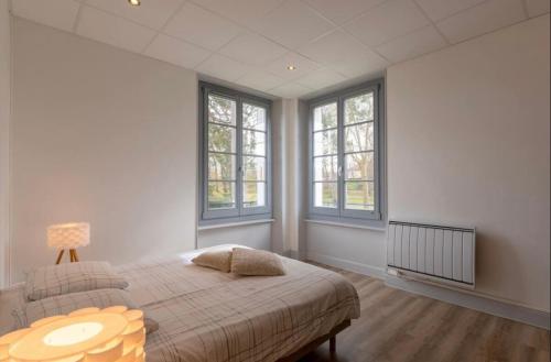 a bedroom with a bed with a table and windows at Résidence Harmonie Appartement N 3 Meublé Avec Petit Déjeuner in Néris-les-Bains