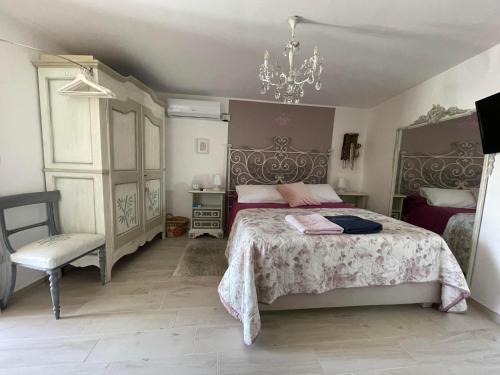 a bedroom with a bed and a chair and a chandelier at THE SECRET GARDEN in Forza dʼAgro