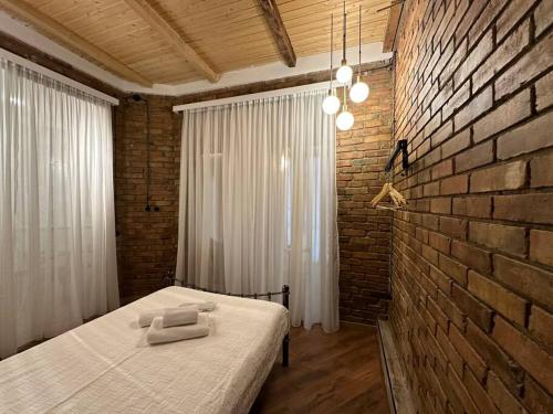 a bedroom with a bed and a brick wall at Сity center Loft style Apartment in Tbilisi City