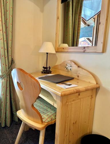 a wooden desk with a chair and a mirror at Hameau des Prodains - Hôtel in Morzine