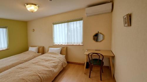 two beds in a room with a desk and a chair at Guest House Jino - Vacation STAY 15446 in Takayama
