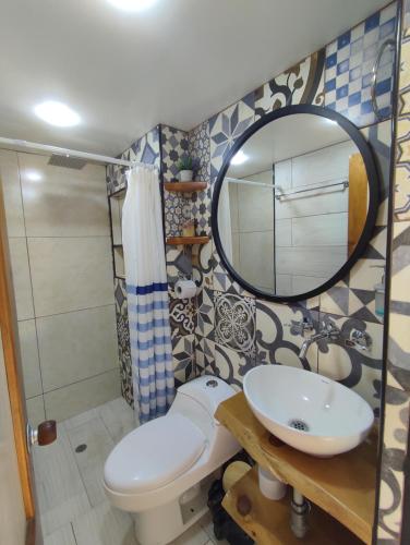 een badkamer met een toilet, een wastafel en een spiegel bij Apartamento en el centro histórico de Tunja con chimenea in Tunja