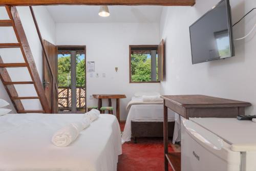 a room with two beds and a flat screen tv at Pousada Trilha do Mar in Praia do Frances