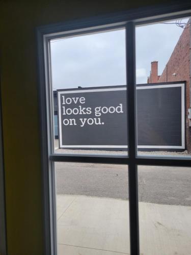 Ein Fenster mit einem Schild, auf dem steht, dass Liebe gut auf dir steht. in der Unterkunft The Huber The Archive Lofts in Marion