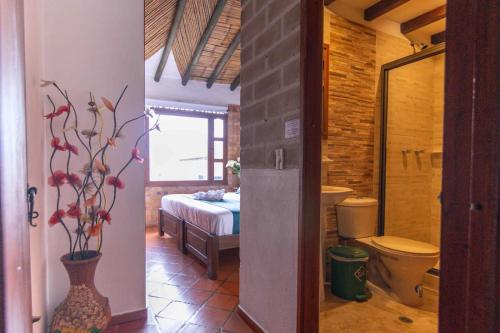 a bathroom with a toilet and a bedroom with a bed at Bello Hogar Hospedaría VDL in Villa de Leyva