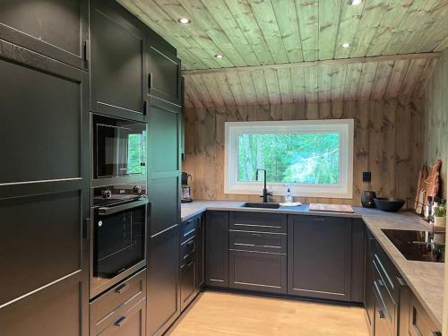 a large kitchen with black cabinets and a window at Stor hytte med fantastisk utsikt 