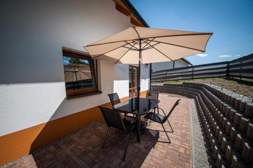 a table and chairs under an umbrella on a patio at Apartmány na Žlábku in Horní Planá