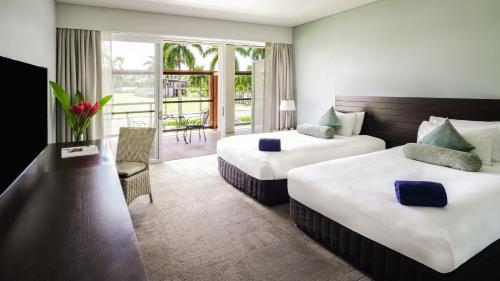 スバにあるグランド パシフィック ホテルのベッド2台とバルコニーが備わるホテルルームです。