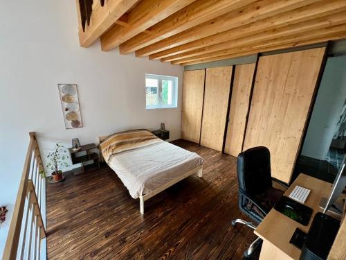 1 dormitorio con cama, suelo de madera y escritorio en Capstay La Louvière, en La Louvière