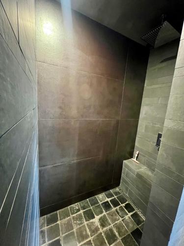 a bathroom with a shower with a tiled floor at Capstay La Louvière in La Louvière