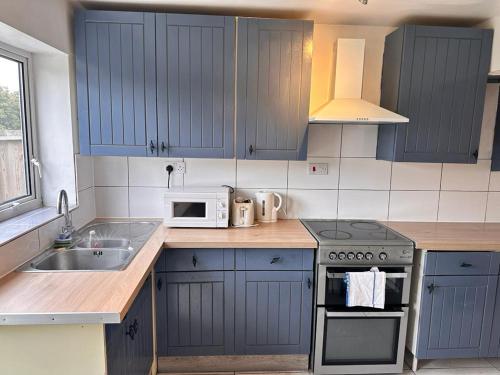 a kitchen with blue cabinets and a stove and a sink at East Lodge - Spacious 4 bed house in Basildon