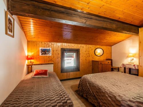 - une chambre avec 2 lits dans une pièce dotée de murs en bois dans l'établissement Appartement cozy avec Wi-Fi, parking et animaux admis - FR-1-671-72, aux Gets