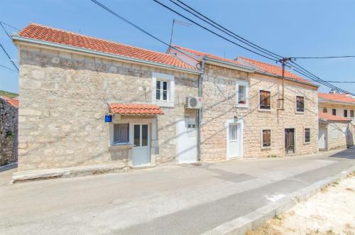 ein Steinhaus mit weißen Türen auf einer Straße in der Unterkunft House Jozo in Marina