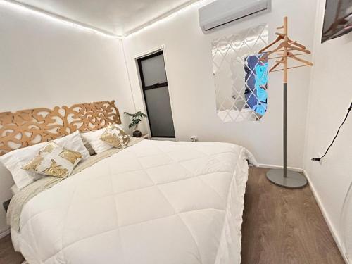 a white bedroom with a large white bed in a room at Estadía en Villa alemana Opción a jacuzzi Golden BeeHouse in Villa Alemana