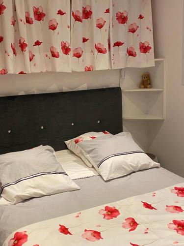 1 dormitorio con 2 camas con flores rojas en las sábanas en les alouettes, en Aurillac