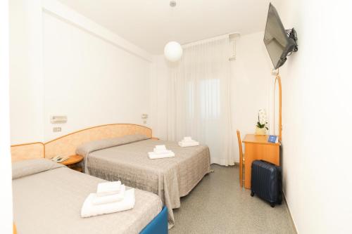 een hotelkamer met 2 bedden en een televisie bij Hotel Saint Louis in Rimini