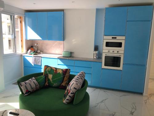 une cuisine avec des placards bleus et un canapé vert dans l'établissement Promenade des anglais 20 mètres, à Nice