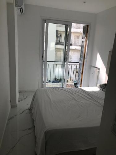 une chambre avec un lit et une grande fenêtre dans l'établissement Promenade des anglais 20 mètres, à Nice
