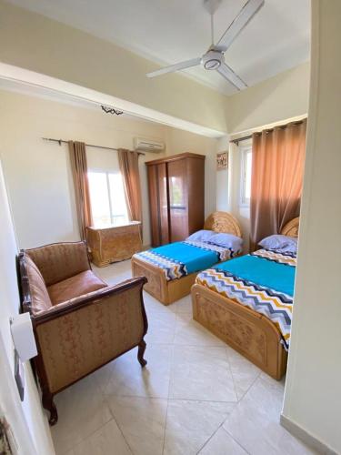 a bedroom with three beds and a chair and a couch at فيلا اول صف بحر مارينا الساحل الشمالي العلمين برايفت بول in El Alamein