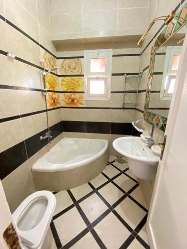a bathroom with a tub and a toilet and a sink at فيلا اول صف بحر مارينا الساحل الشمالي العلمين برايفت بول in El Alamein