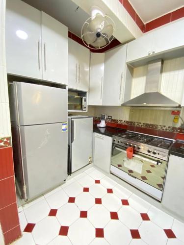 a kitchen with white appliances and red and white tile floors at فيلا اول صف بحر مارينا الساحل الشمالي العلمين برايفت بول in El Alamein