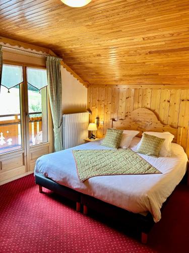 a bedroom with a large bed with a wooden ceiling at Hameau des Prodains - Hôtel in Morzine