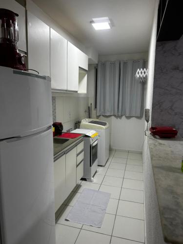 a kitchen with white cabinets and a white tile floor at Apt da Leily in São Luís