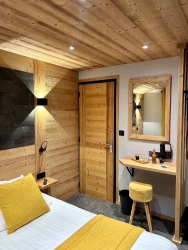 a bedroom with a bed and a desk and a mirror at Hameau des Prodains - Hôtel in Morzine