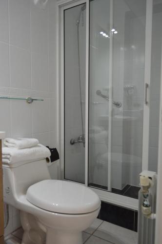 y baño blanco con ducha y aseo. en Hotel Rukalaf, en Chillán