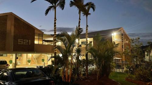 a car parked in front of a building with palm trees at Lancaster Court Motel in Brisbane