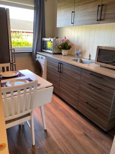 a kitchen with a table and a sink and a microwave at comfortable apartment in a quiet area in the city center in Skien