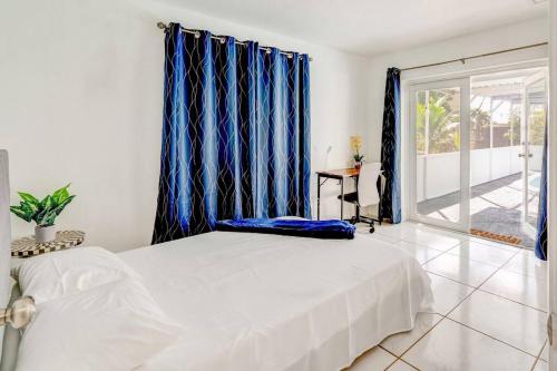 1 dormitorio con cama blanca y cortinas azules en Sunrise Getaway, en Sunrise