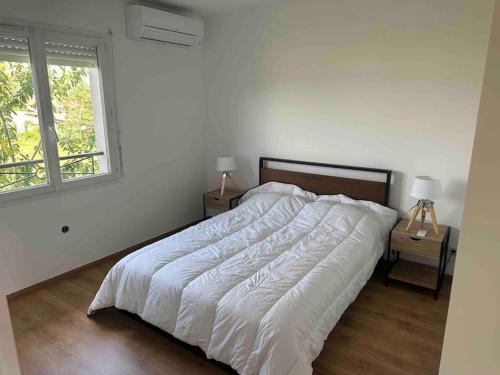 une chambre blanche avec un lit et une fenêtre dans l'établissement Maison 100m2 4 chambres avec piscine jardin paysage, à Gujan-Mestras