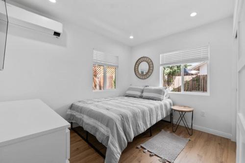 a white bedroom with a bed and a mirror at Modern Cottage, Hot Tub, Bistro Patio, Putting Green, Walk to All! in Thousand Oaks