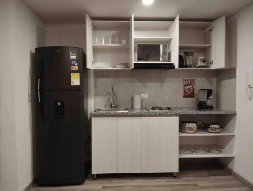 a kitchen with a black refrigerator and white cabinets at Apartaestudio Centro Historico Bogota in Bogotá