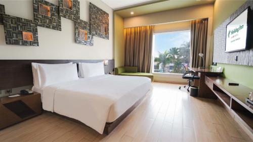a bedroom with a large white bed and a desk at Holiday Inn Cikarang Jababeka by IHG in Cikarang