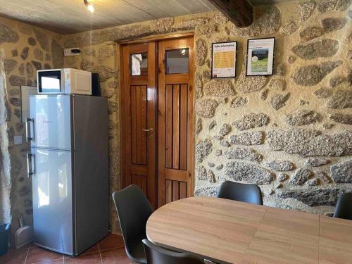 a dining room with a table and a refrigerator at Petra's House Gerês in Geres