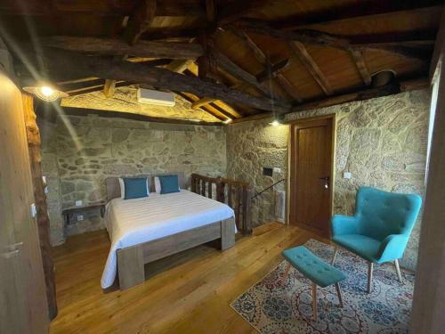 a bedroom with a bed and a blue chair at Petra's House Gerês in Geres
