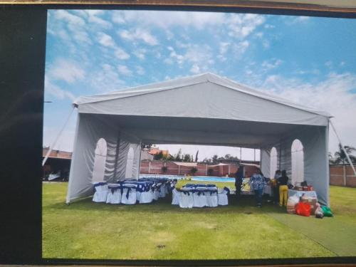 Tienda blanca con mesas y sillas en un campo en Casa para fin de semana, en Monterrey